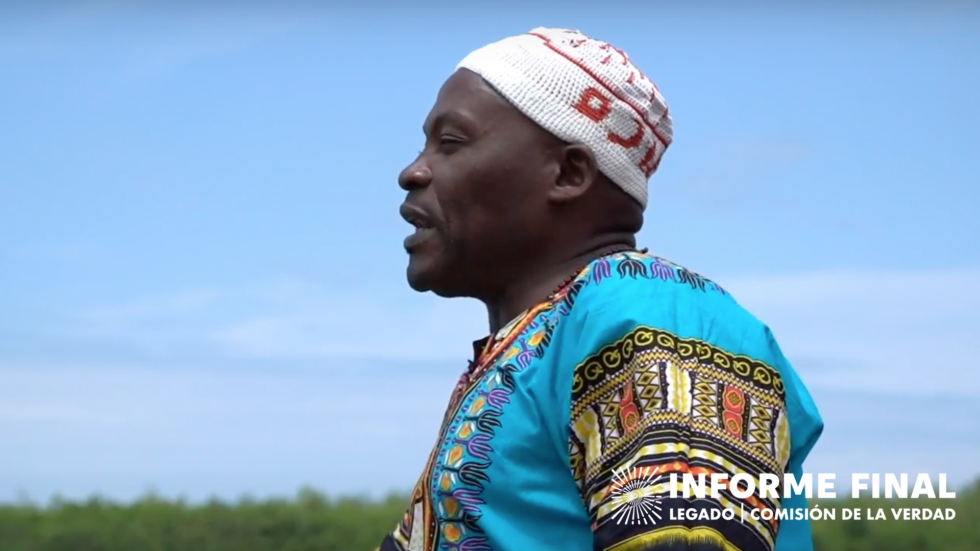 Hombre afro de perfil, con traje tradicional y gorro de lana mira al horizonte, al fondo el cielo