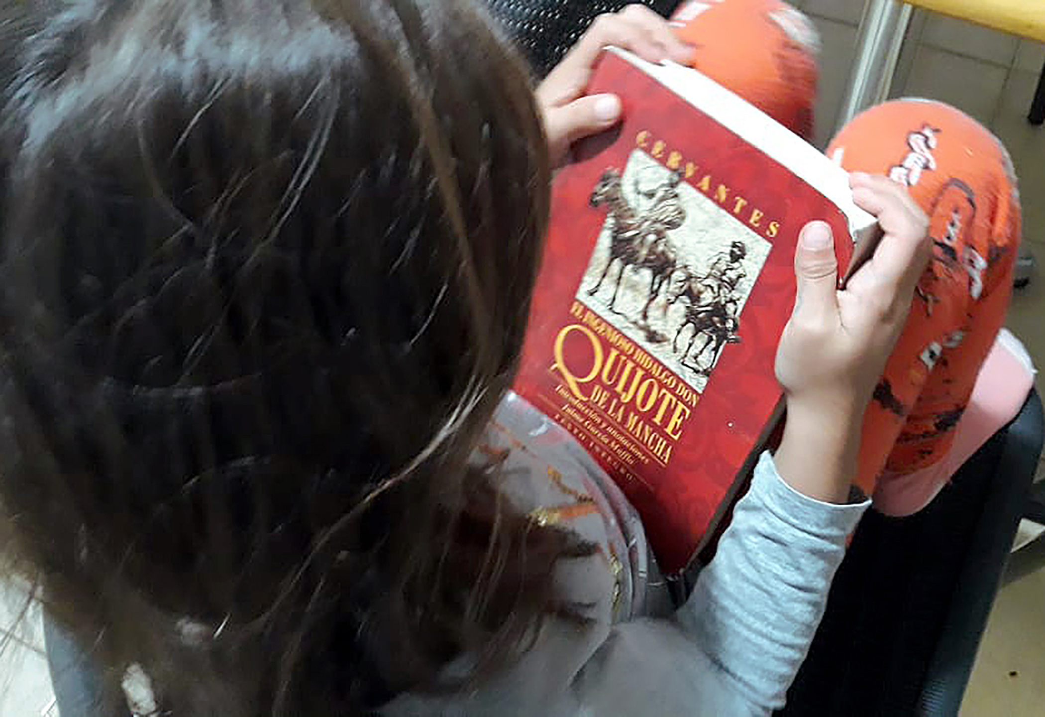 Niña sosteniendo El Quijote de la Mancha con ilustración 