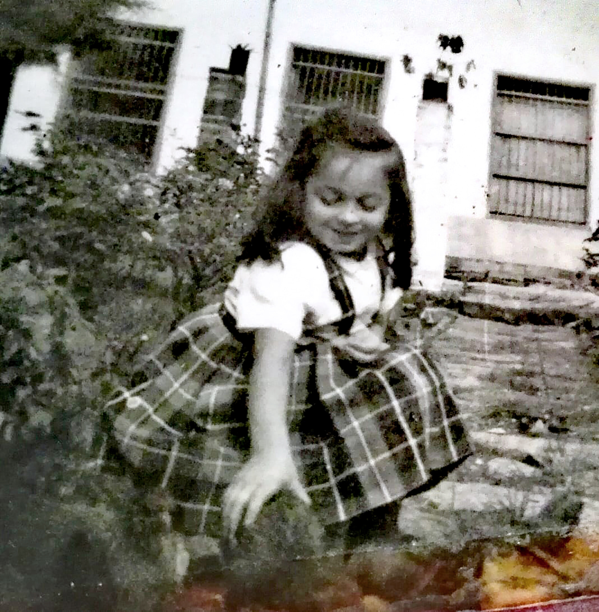 Foto antigua de niña en uniforme de colegio en un jardín