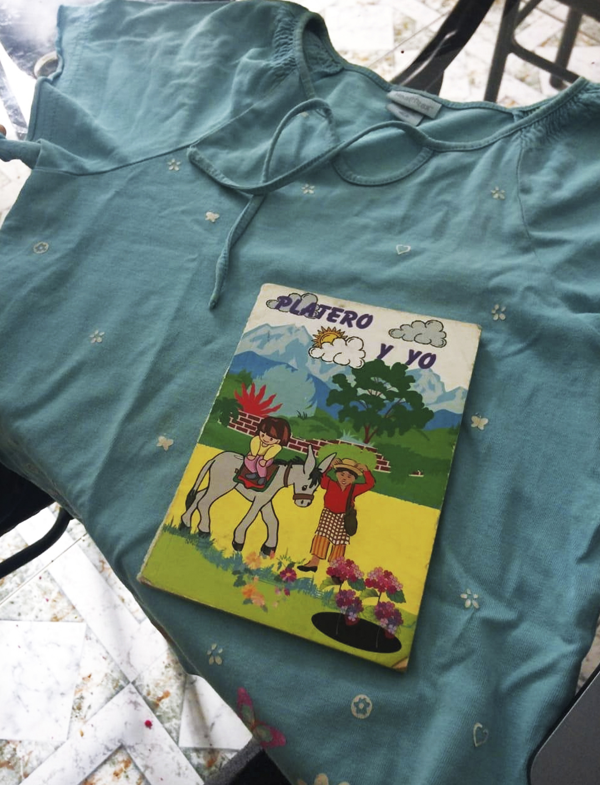 Libro Platero y yo sobre una bandera de Colombia con ilustración de paisaje, niña, niño y burro