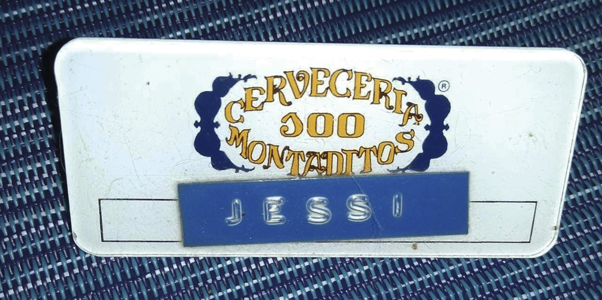 Escarapela con texto: “cervecería 100 montaditos” y el nombre Jessi