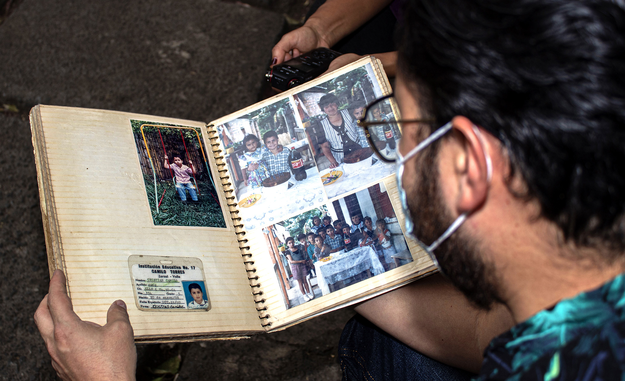 Hombre viendo álbum con fotos de cumpleaños,  niño en un columpio y carnet de colegio