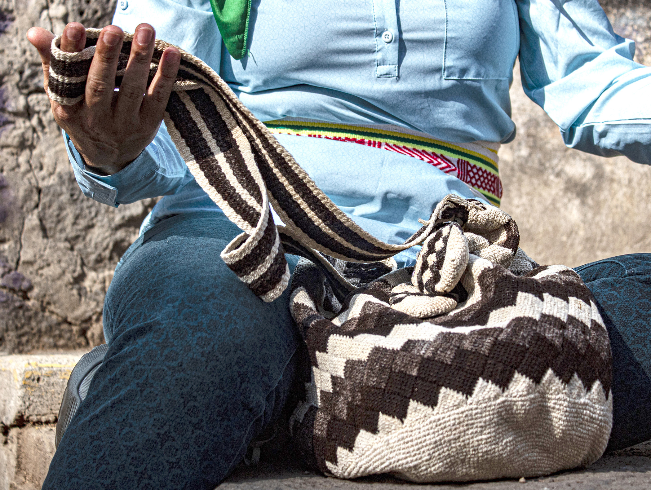 Mujer sostiene la correa de una mochila tejida. Detalle