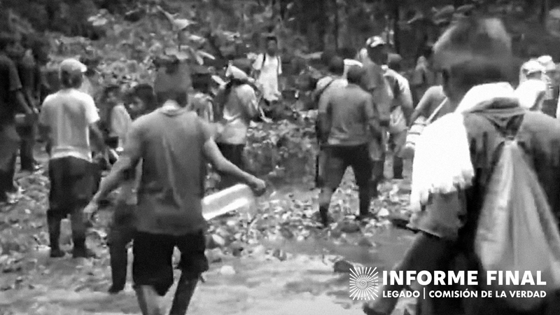 En blanco y negro, personas de comunidad indígena se desplaza por terrenos cercanos a un río