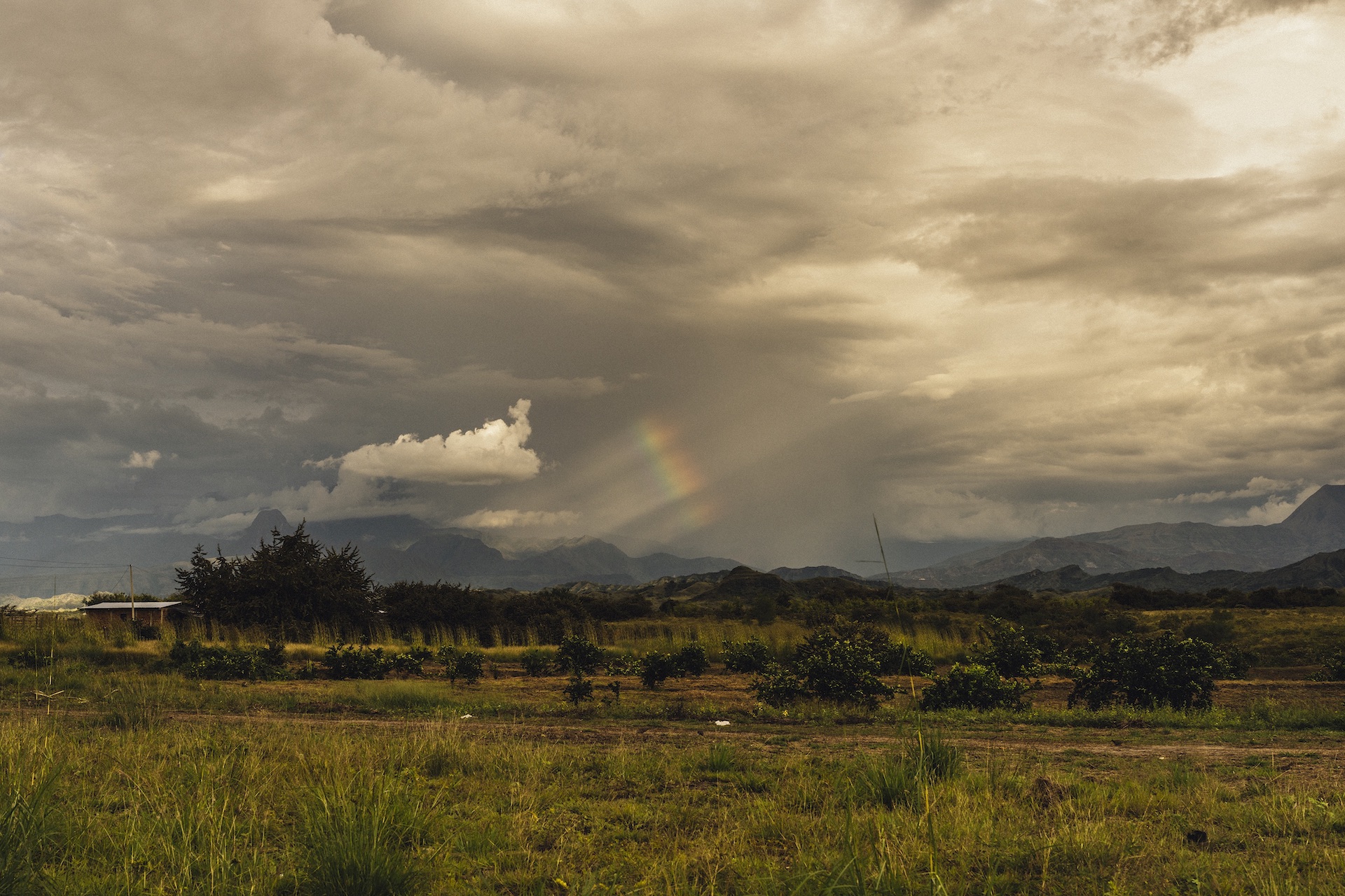 Atardecer en el campo, paisaje con montañas y el cielo nublado con un arcoíris