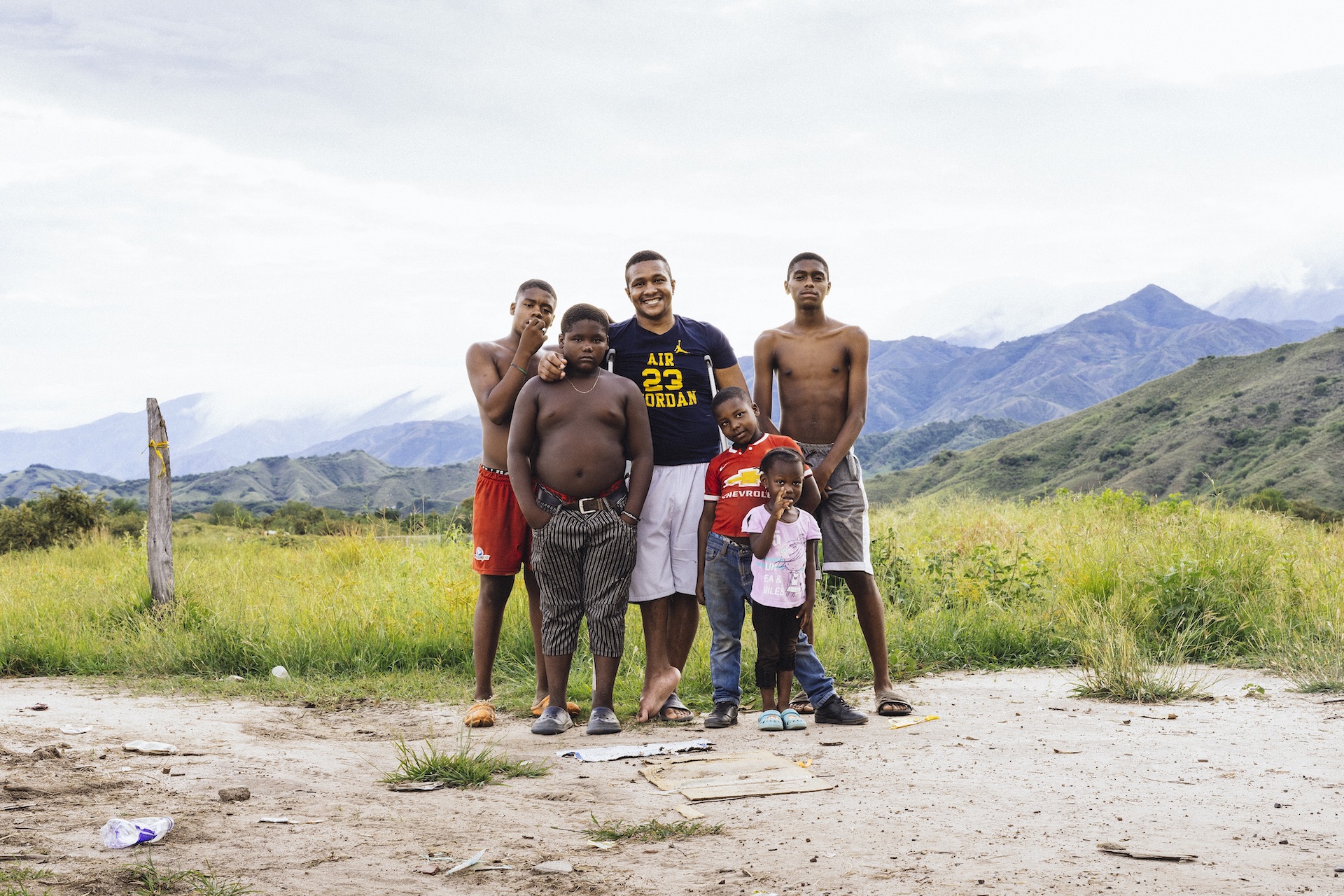 Grupo de tres jóvenes, un hombre y dos niños. Atrás montañas y el cielo nublado